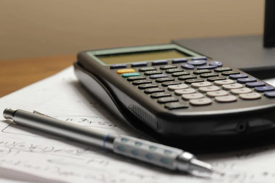 Calculator and mechanical pencil resting on a notepad